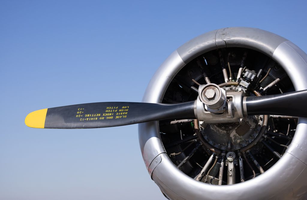 Detailed view of a classic airplane propeller with visible text under a clear blue sky.