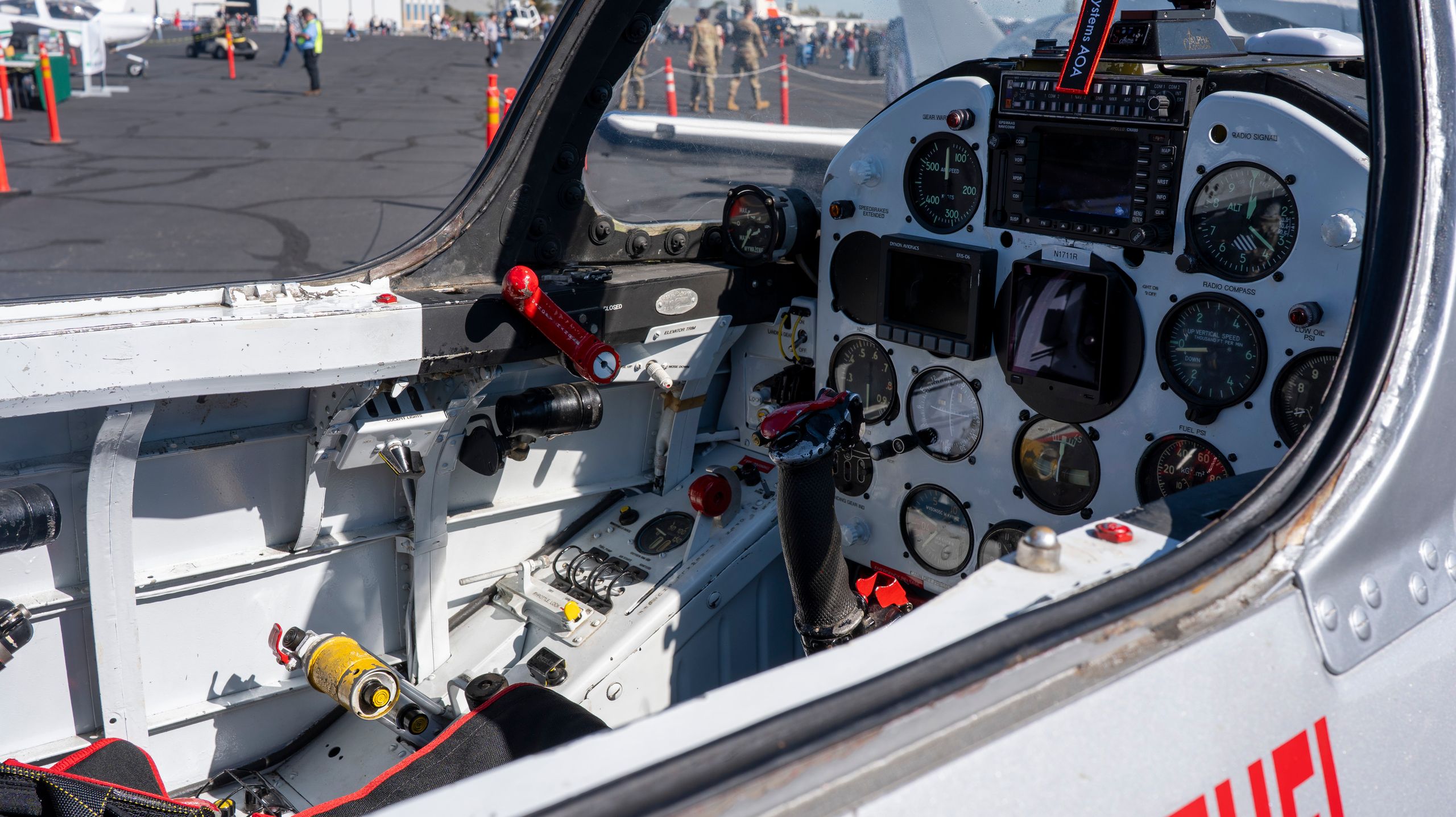 Inside view of a vintage aircraft cockpit at an airshow, showcasing gauges and controls.